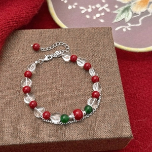 Close-up of handmade beaded bracelet with red pearls and green chalcedony on vintage box