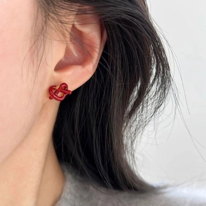 Elegant red knotted heart stud earrings in gold plating worn by a female model