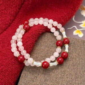 Detailansicht von handgefertigten Perlenarmbändern mit Rosenquarz und roten Akzenten