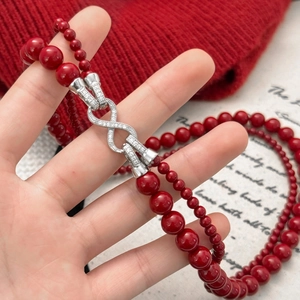 Collar de doble capa de perlas rojas con dije de infinito brillante en fondo invernal
