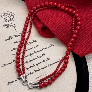 Collar de doble capa de perlas rojas con cierre de infinito sobre fondo romántico