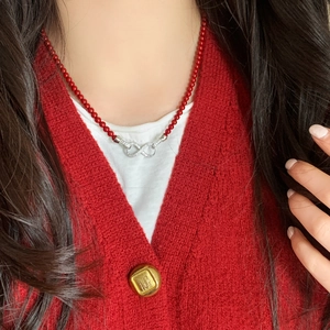 Detalle del collar de perlas rojas con colgante de infinito y cristales brillantes