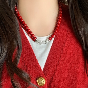 Detalle de collar de doble capa con perlas rojas y cierre de infinito con diamantes