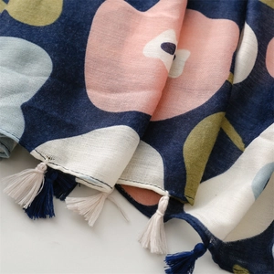 Dettaglio di sciarpa blu in cotone con stampa floreale e texture di frange bicolore