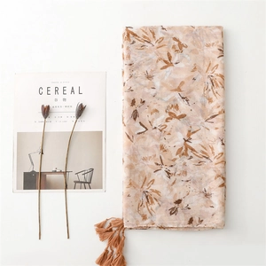 Lightweight apricot floral cotton linen scarf with tassels in a minimalist flat lay