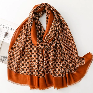Orange scarf with geometric chain patterns and soft frayed edges on white background