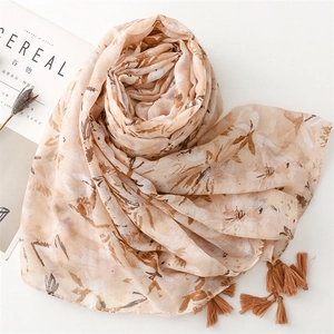 Detailed view of orange cotton linen scarf with floral print and fringe tassels