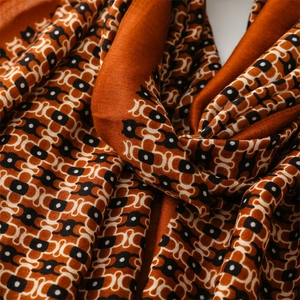 Detail shot of burnt orange scarf with geometric patterns and soft woven texture