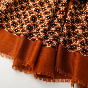 Close-up of caramel geometric pattern scarf with fine fringe detail and soft fabric texture