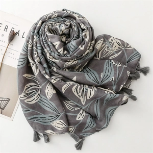 Détail d'une écharpe gris foncé avec motifs floraux et finitions élégantes à franges