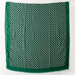 Close-up of dark green square scarf with geometric floral print and delicate fringe edges