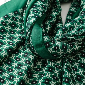 Macro detail of geometric green scarf fabric showing fine fiber texture and hemmed edges