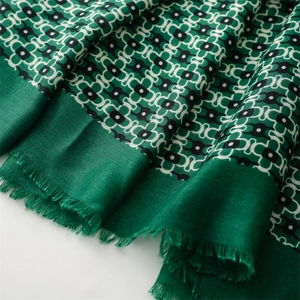 Detailed close-up of emerald green scarf with geometric patterns and fringe edges