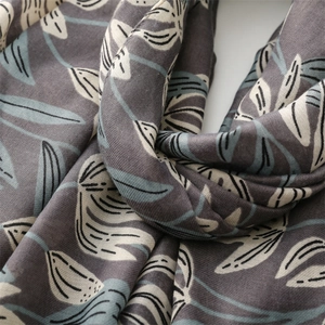 Détail du motif floral et de la texture tissée douce sur une écharpe en coton gris