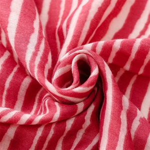 Detail of red and white striped cotton scarf fabric showing soft knit texture and fringe