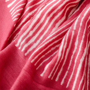 Close-up of red cotton scarf with artistic white vertical stripes and woven texture