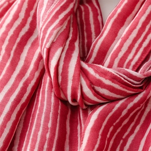 Detail of soft red and white striped cotton-linen scarf showing fabric texture and fringe