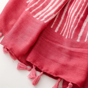 Detail of pink cotton scarf with white stripes and handmade fringe tassels on the edge