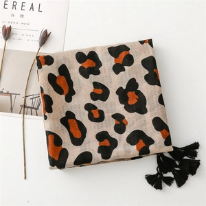Detail of leopard print scarf with black tassels and soft linen-feel texture on white background