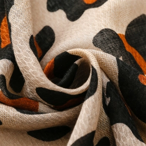 Macro detail of leopard print scarf with soft cotton-linen texture and orange accents