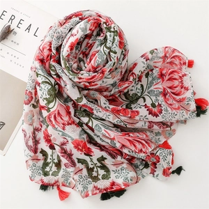 Detail of floral printed scarf with red and green blossoms and fringe tassels