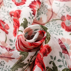 Macro view of floral print on cotton linen scarf with red flowers and green leaves
