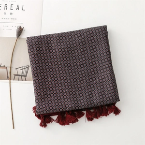 Dettaglio di sciarpa floreale con nappe rosso scuro su sfondo bianco con decori