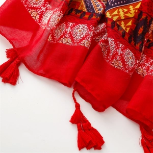 Detail eines Bohème-Schals in Rot mit geometrischen Mustern und weichen Seidenquasten