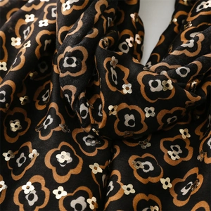 Detailed texture of black cotton-linen scarf featuring golden floral embroidery patterns