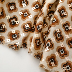 Macro detail of scarf showing golden flower stamping and soft fringed fabric edges