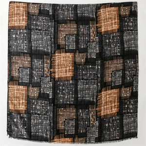 Close-up of geometric patchwork pattern and fringe texture on this warm shawl scarf