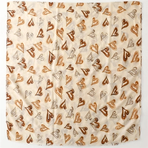 Détail à plat de l'écharpe beige avec motifs de cœurs terreux et bords à franges