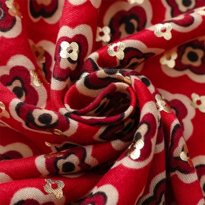 Macro detail of red scarf fabric featuring gold foil flowers and heart floral patterns