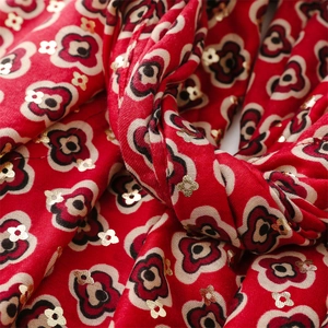 Detail of red fabric with white floral patterns and golden sequins for scarves and shawls