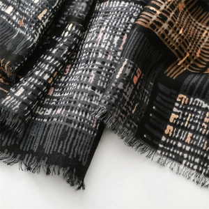 Macro detail of textured black and grey scarf with gold metallic threads and frayed edges