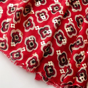 Detail of red floral scarf with gold foil accents and natural fringed edges