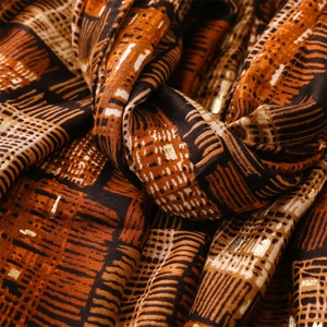Macro detail of scarf showing golden foil web patterns and textured ethnic print fabric