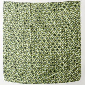 Detailed flat lay of a green silk scarf featuring geometric floral patterns and silky texture