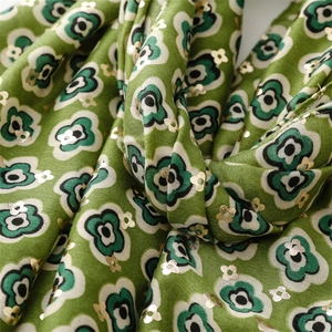 Close-up of linen-feel shawl featuring green floral prints and gold foil accents