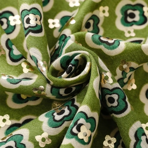 Detail of green scarf fabric with gold leaf flower patterns and soft cotton-like texture