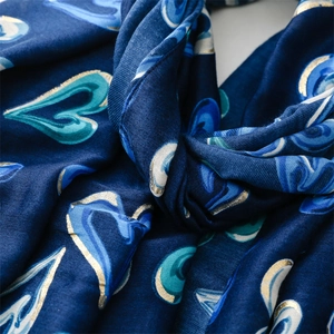 Détail d'un châle bleu marine en coton avec motif cœur doré et texture sergée douce