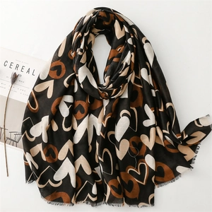 Écharpe noire à motifs de cœur marrons et franges sur fond blanc avec décoration
