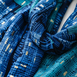Macro view of blue silk scarf with golden foil abstract architecture patterns and texture