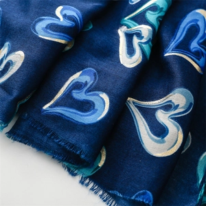 Texture détaillée de l'écharpe bleu foncé avec imprimé cœur doré et bord à franges