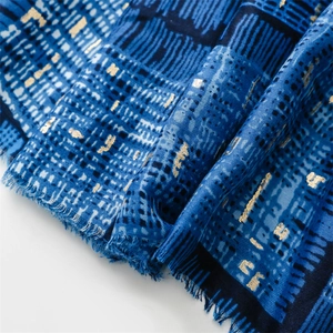 Macro detail of blue scarf with gold foil spider web pattern and fringe edges