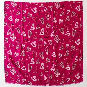 Détail d'une écharpe en coton et lin fuchsia avec motifs de cœurs et franges