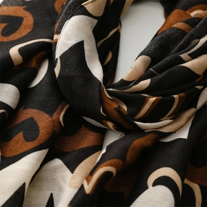 Détail d'une écharpe en soie douce avec motifs de cœurs géométriques café et noir abstraits