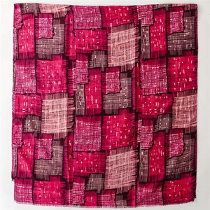 Detail of artistic geometric patterns on a warm pink and burgundy cotton-linen shawl
