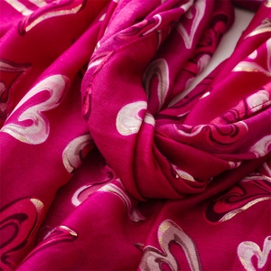 Gros plan sur l'écharpe rose en lin et coton avec motifs de cœurs dorés et texture douce