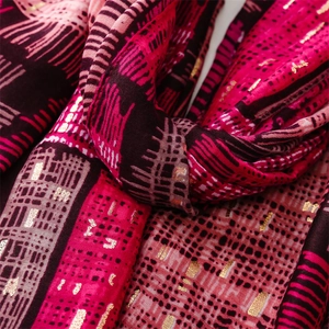 Detail view of woven pink scarf with gold foil accents and abstract geometric patterns